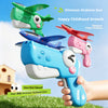 A hand holds a blue Dinosaur Airplane Gun toy, with several foam airplane models flying in the air.