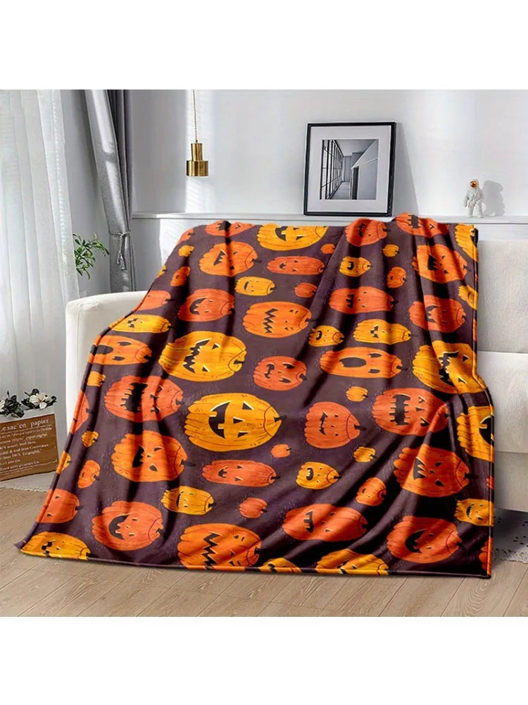 A dark brown flannel throw blanket featuring an orange pumpkin print, displayed on a white sofa.