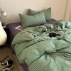A green and white striped duvet cover set with matching pillowcases on a bed.