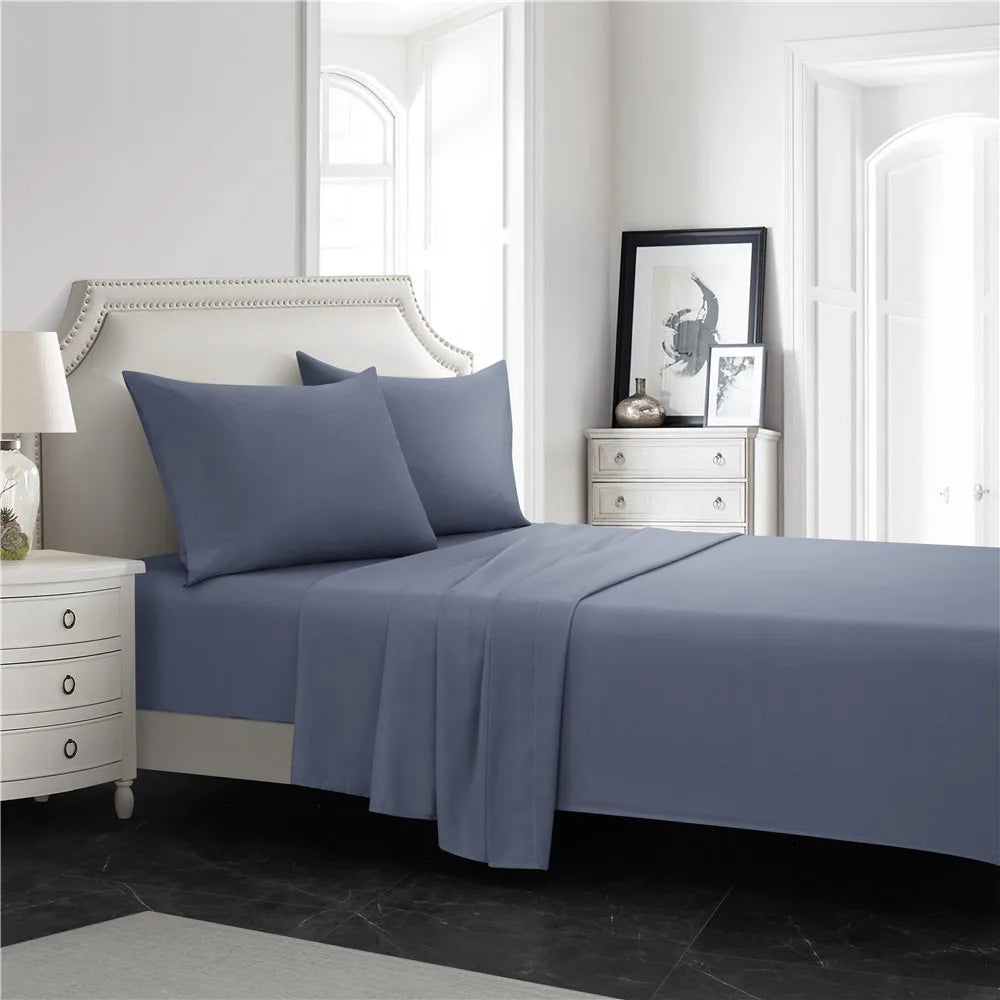 A bedroom featuring a bed dressed in soft blue microfiber bedding with a matching fitted sheet, flat sheet, and pillowcases.