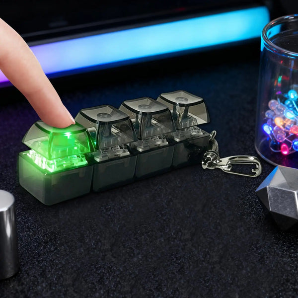 Una mano presiona un llavero teclado táctil verde con teclas iluminadas sobre una superficie oscura.
