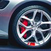 Close-up of a silver car wheel with red and white reflective safety stickers on the tire tread.