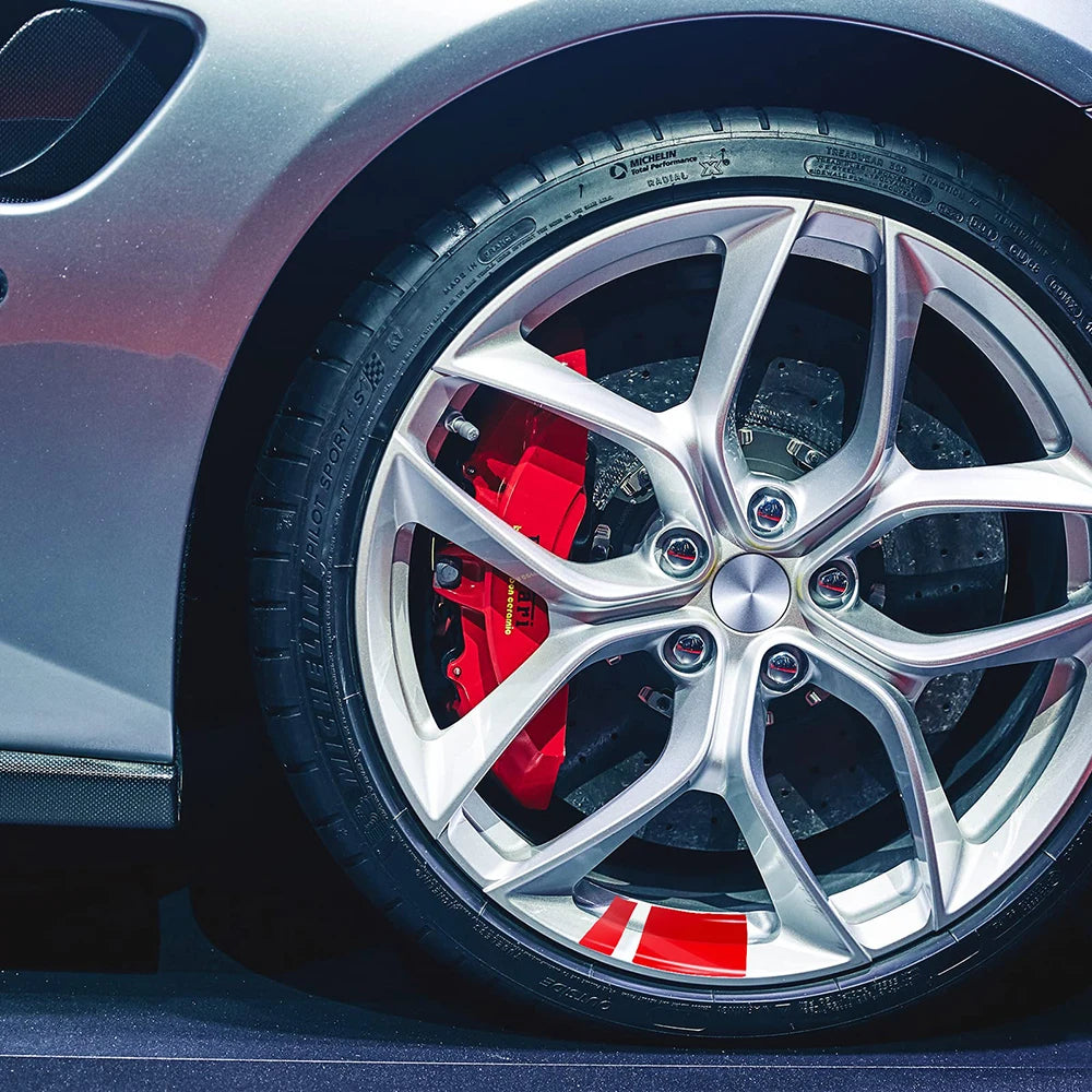 Close-up of a silver car wheel with red and white reflective safety stickers on the tire tread.