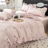 A pink duvet cover set with black heart print and matching pillowcases shown on a bed.