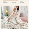 A person is relaxing on a bed covered with a fluffy white fleece throw blanket, enjoying the comfort of the moment.