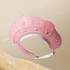 A pink adjustable baby bath shampoo shield cap with ear protection shown against a light background.