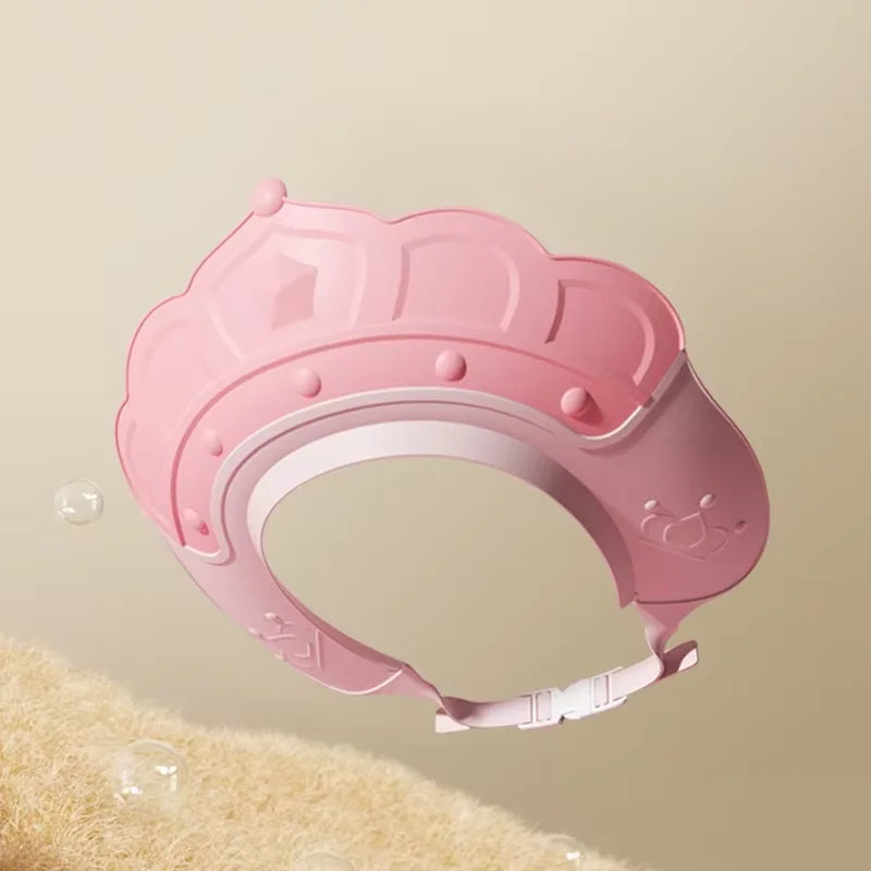 A pink adjustable baby bath shampoo shield cap with ear protection shown against a light background.