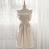A cream-colored kitchen apron made of cotton linen with lace trim and ruffled sleeves displayed on a mannequin.
