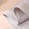 A close-up of a light beige, ribbed baby burp cloth folded and displayed on a soft background.