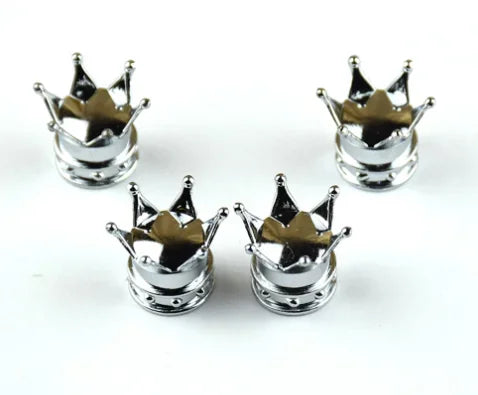 A set of four silver universal crown valve caps with decorative points.