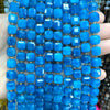 A hand holds a strand of bright blue natural stone square faceted beads for jewelry making.