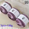 Three skeins of purple glitter yarn are displayed on a light surface.