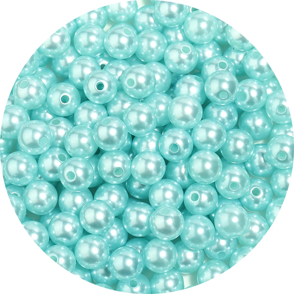 A close-up view of small, round, light blue imitation pearl beads for jewelry making.
