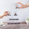 A hand is placing a figurine into a clear acrylic display case for collectibles.