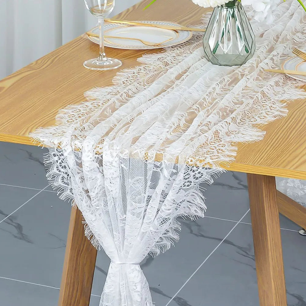 Vintage white embroidered floral lace table runner draped on a wooden table.