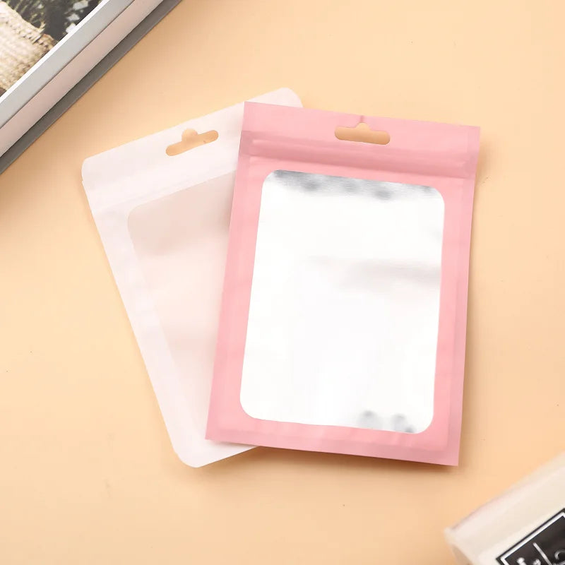 A pink Mylar ziplock bag with a clear window is shown next to a white bag on a light background.