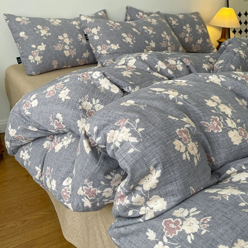 A gray floral printed duvet cover set with matching pillowcases displayed on a bed.