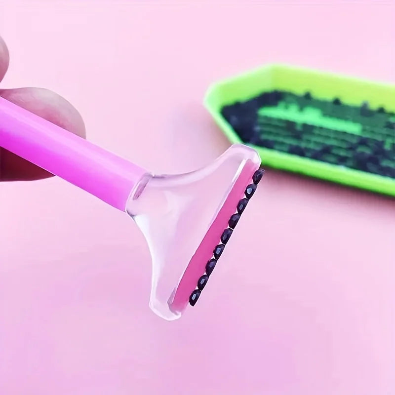 A pink applicator pen for a diamond painting kit is shown next to a green storage case.