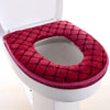 Una cubierta de asiento de inodoro impermeable de color rojo intenso y suave instalada en un inodoro blanco.