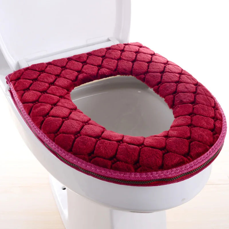 Una cubierta de asiento de inodoro impermeable de color rojo intenso y suave instalada en un inodoro blanco.