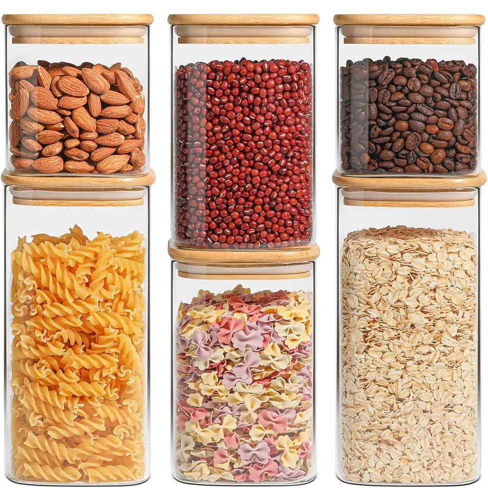 A collection of dried foods including almonds, red beans, pasta, and various grains stored in airtight glass canisters with b
