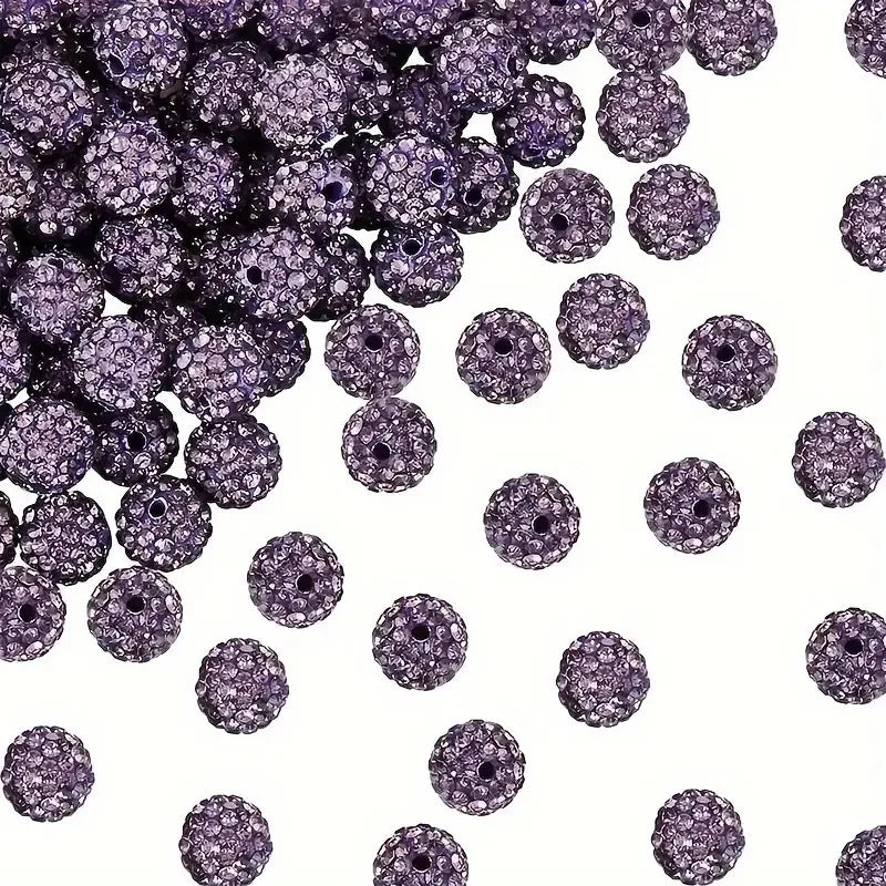 A pile of small, round, purple crystal clay beads for DIY jewelry and craft projects.
