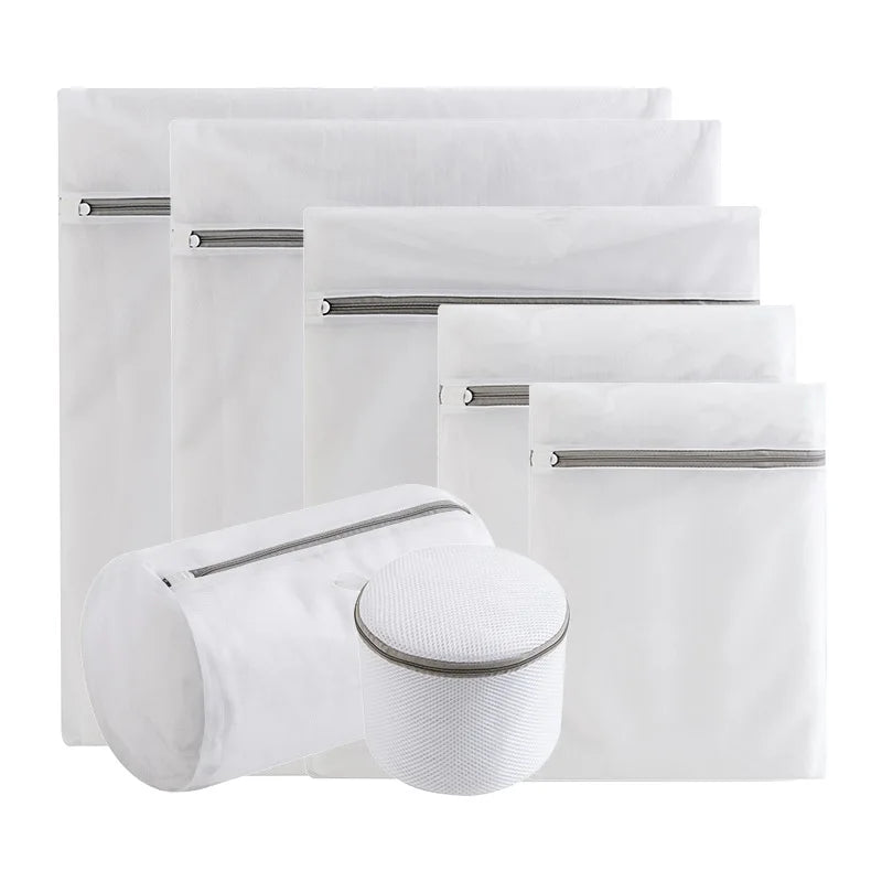 A stack of four white fine mesh laundry bags for delicates, some closed and some open.