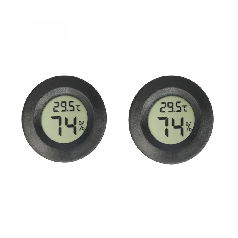 A close-up view of a black mini digital hygrometer thermometer displaying 29.5°C and 74% humidity.