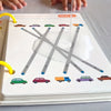 A page from a reusable magic tracing workbook showing various colored cars and vehicles drawn with lines.