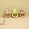 Three silicone baby teether toys shaped like flowers and grapes in pink, yellow, and pink.