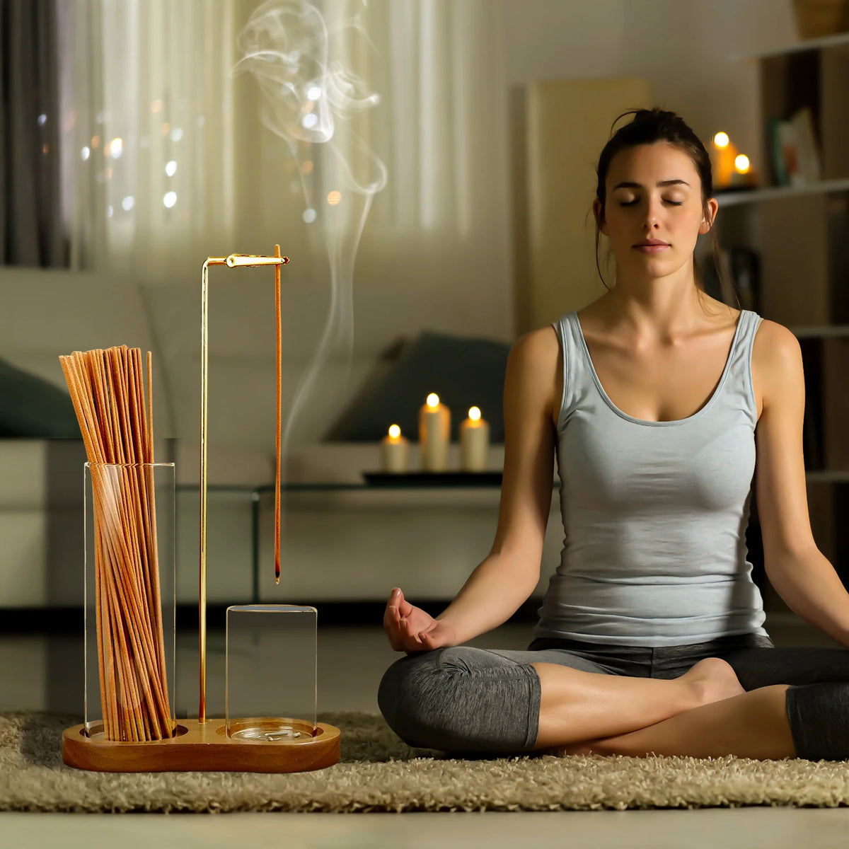 A woman sits in meditation with a tall glass incense holder on a wooden base.