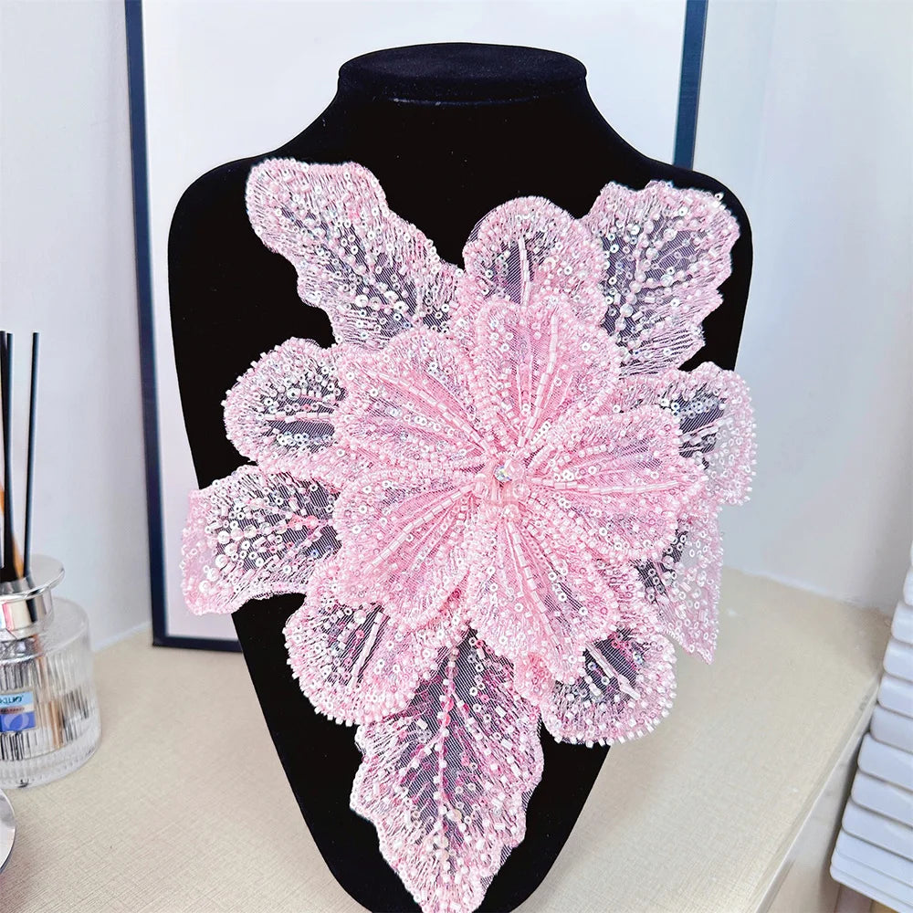 Pink floral lace applique patch with sequins displayed on a black mannequin.