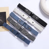 A collection of five stretch elastic belts in black, gray, and white leather with metal buckles displayed on a light backgrou