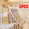 A hand is hanging light beige trousers on a multi-layer wooden hanger rack.