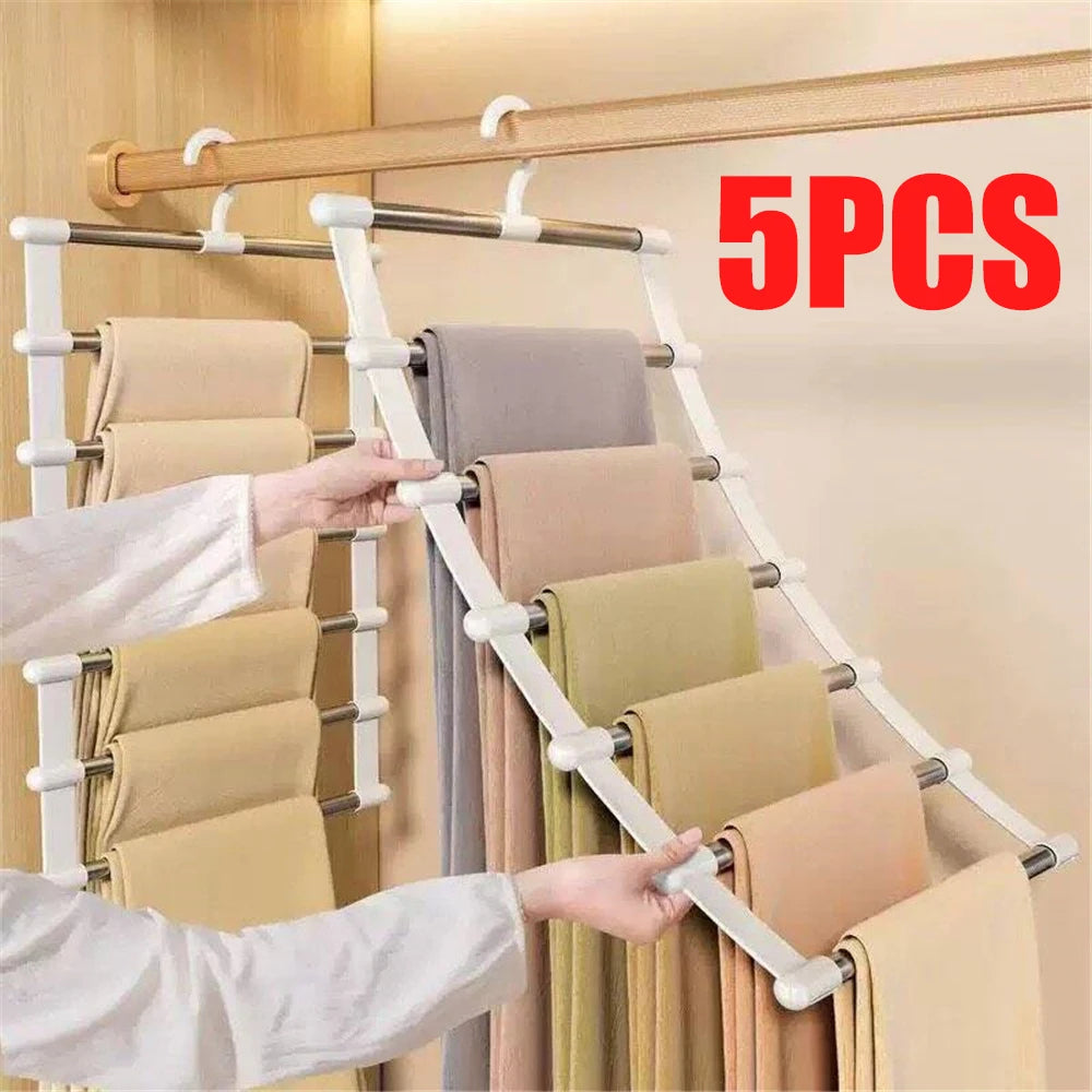 A hand is hanging light beige trousers on a multi-layer wooden hanger rack.