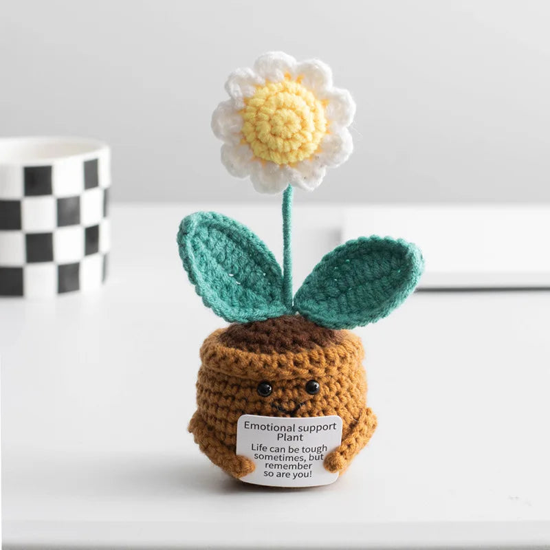 Handmade crochet plant decoration featuring a white flower and green leaves on a brown body.