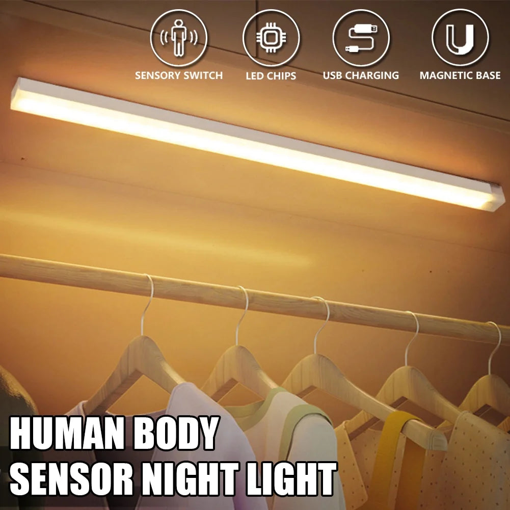 A long, white LED sensor night light is shown illuminating a wooden clothing rack in a store setting.