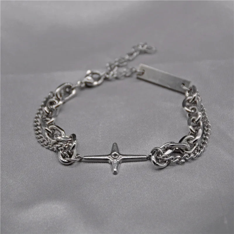 Bracelet argenté à double couche avec motif étoile et croix sur maillons.