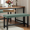A green stretch jacquard bench cover with a brown wooden table and a white rug.