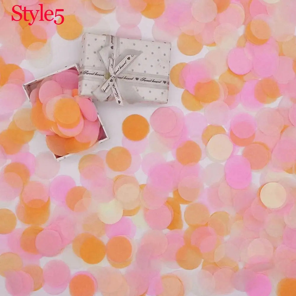 Pinkes und orangefarbenes Taschentuchpapier-Confetti auf einer weißen Oberfläche mit einer kleinen Geschenkbox.