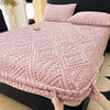 A pink textured plush mattress cover with an elastic edge is shown on a bed.