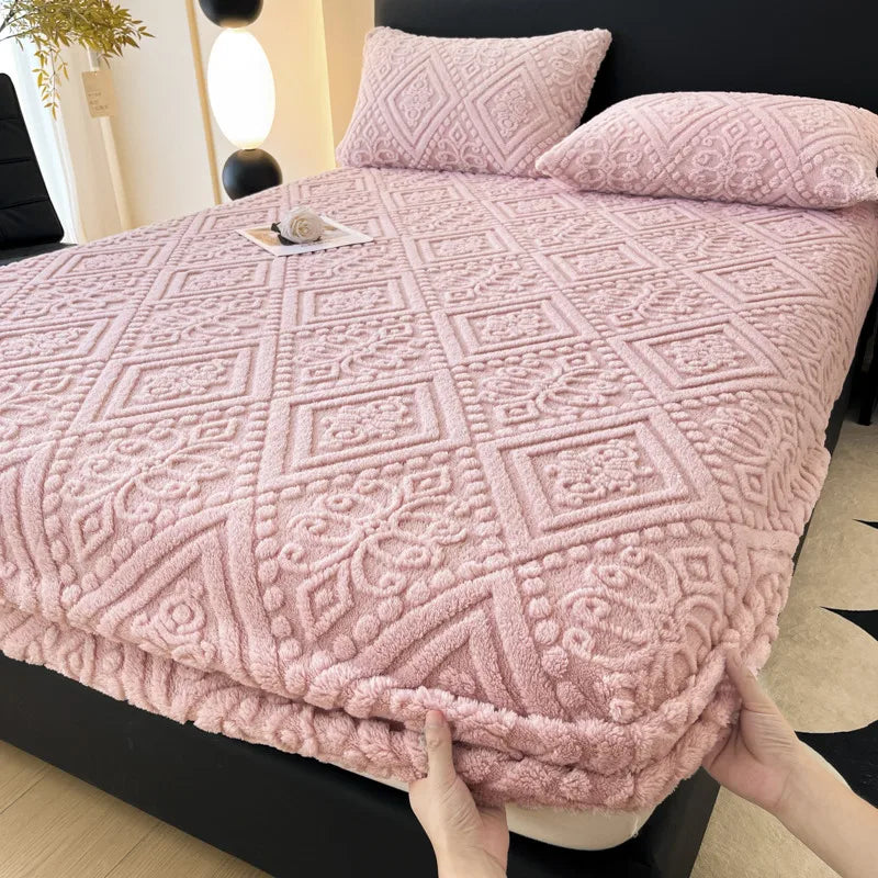 A pink textured plush mattress cover with an elastic edge is shown on a bed.