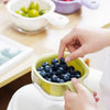 A hand is using a yellow fruit washing basket to hold blueberries for washing or draining.