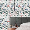 A close-up of a bedroom featuring a headboard and a pendant light, decorated with boho leaf peel-and-stick wallpaper.