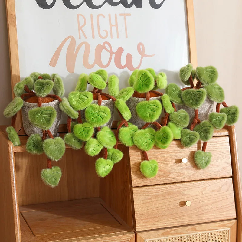 A potted plant featuring soft faux green leaves displayed on a wooden cabinet.