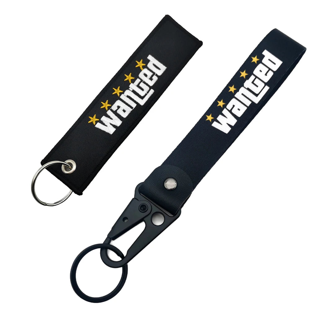 Black nylon keychain with embroidered wanted text and a steel spring clip