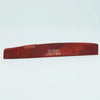 A reddish-brown cow bone acoustic guitar bridge saddle with the inscription Guyler ATR-7430