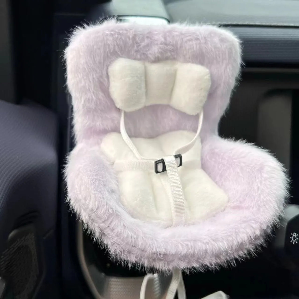 A fluffy lavender doll seat car vent decoration with white padding and ties.