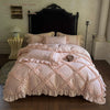 A pink ruffled duvet cover set with three pillowcases displayed on a bed against a dark headboard.