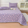 Purple floral quilted bedspread with pink flowers and a white picket cabinet in a bedroom setting.